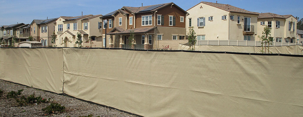 Temporary fence rental near Creston, California with beige privacy screen in front of homes.